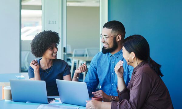 3 people smiling and talking at work